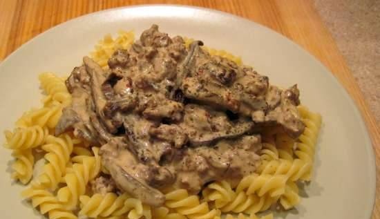 Pasta con funghi e agnello tritato in umido in salsa cremosa