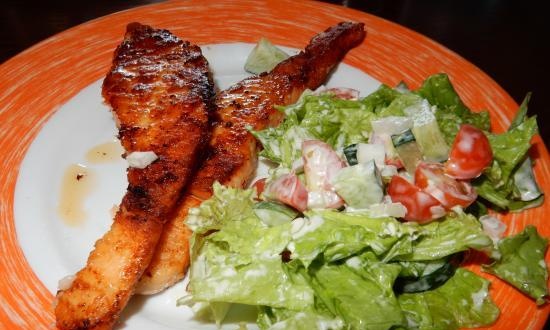 Pescado frito sobre pergamino en una sartén