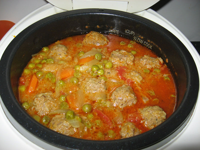 Polpette con piselli e carote in una pentola a cottura lenta